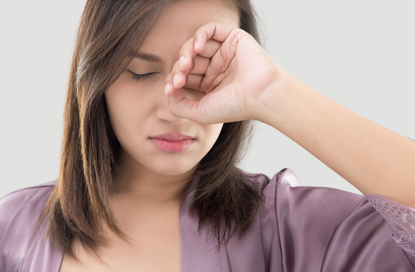 A person with blepharitis rubbing their itchy irritate eyes with the back of their hand