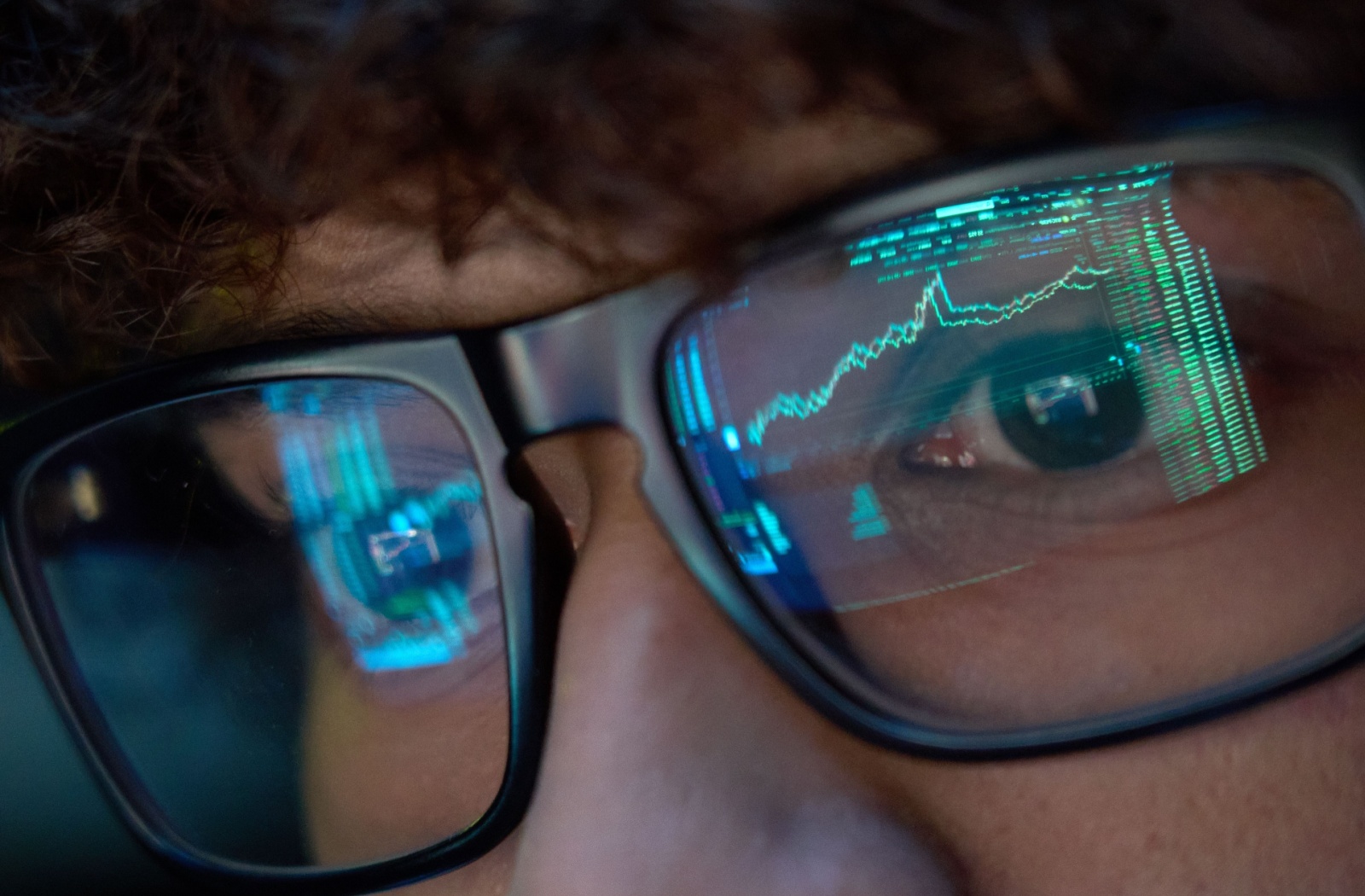 Close-up of a computer screen reflected in an office worker's glasses.